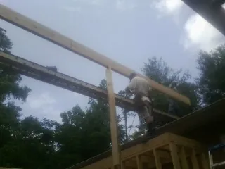 Carpenter setting a ridge beam over a new addition frame — Ice Dam Removal by Roofing Brothers in Crapo