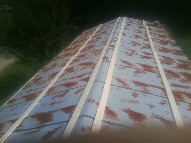 Rusted metal roof panels with new wood purlins before replacement — Storm Damage Roof Repair in Crapo by Roofing Brothers