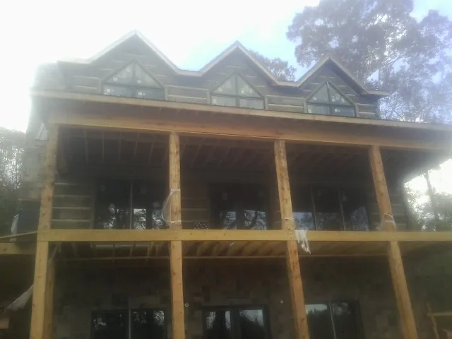 Dormers and porch framing on a large log home under construction — Roof Coating work by our crew in Crapo