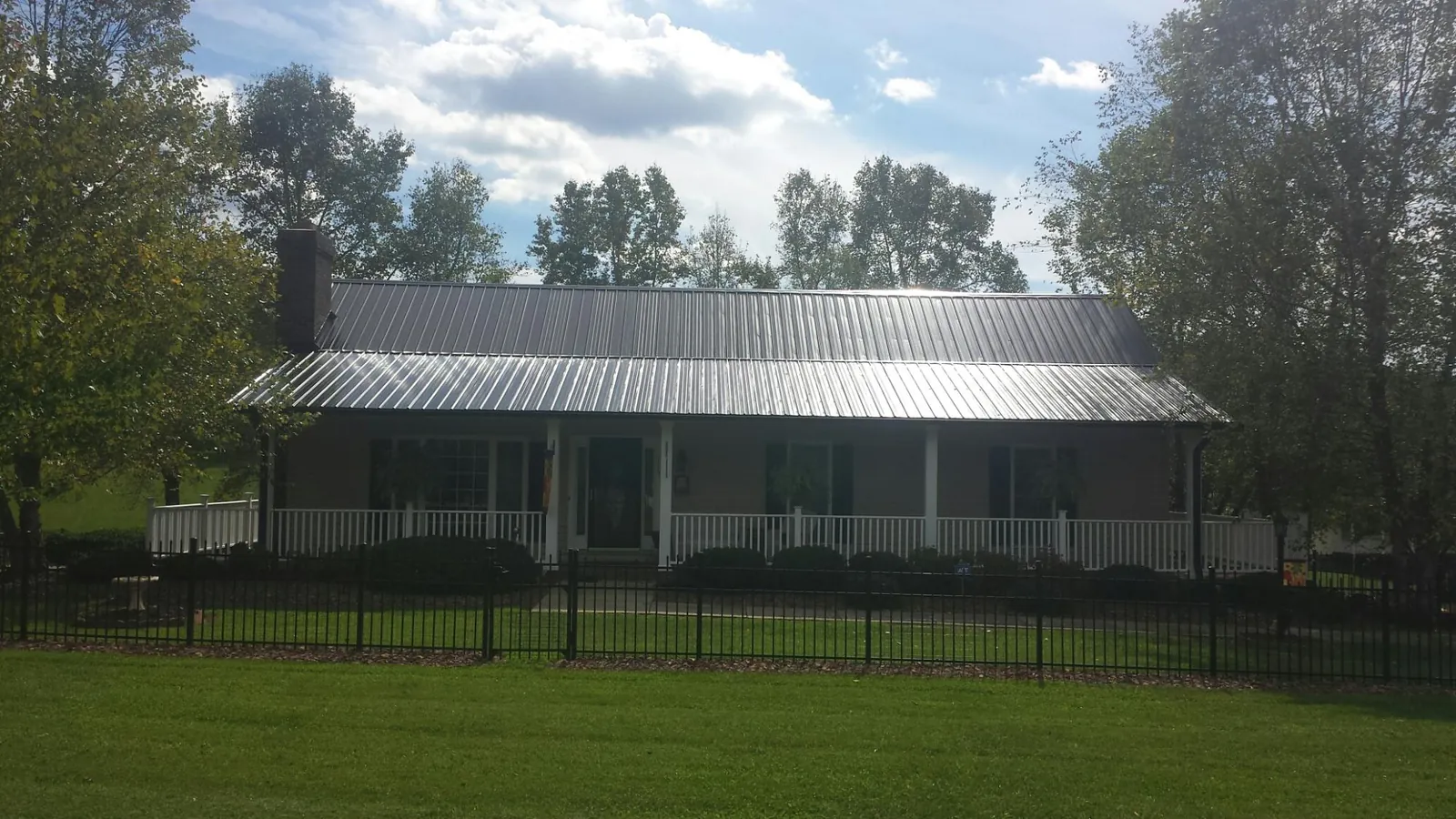 Gray metal roof on a brick ranch with a full width front porch — Gutter Guard Installation work by our crew in Crapo