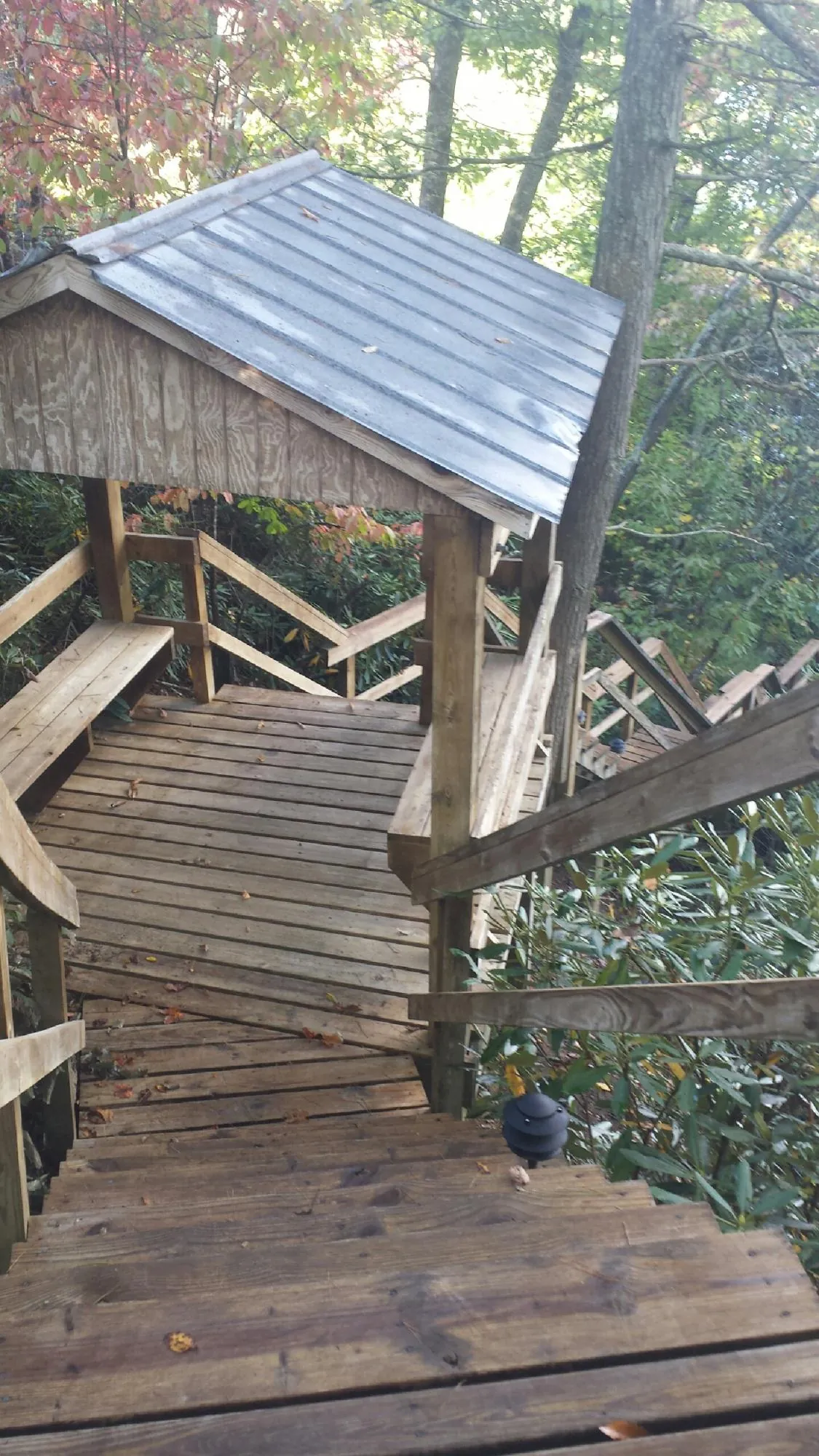 Metal roofed shelter over wooden steps on a wooded walkway — Skylight Repair & Installation work by our crew in Crapo