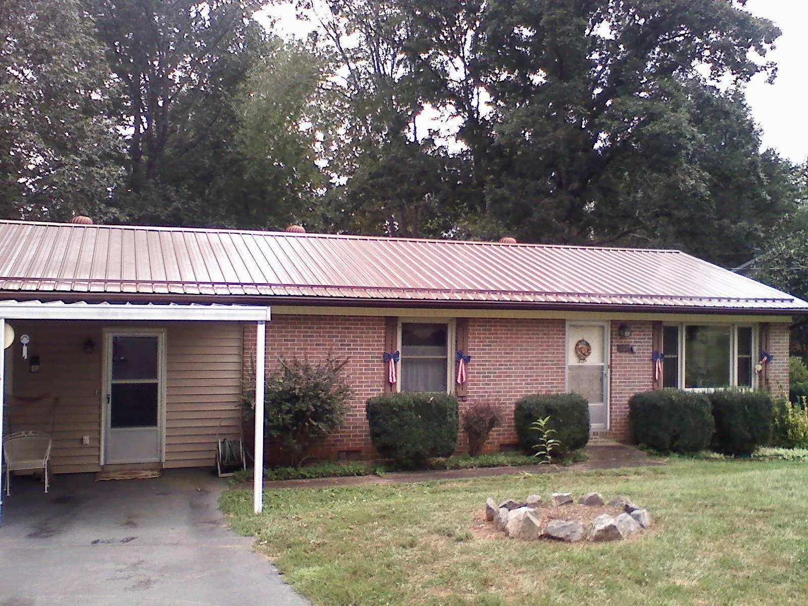 Bronze metal roof and carport on a brick ranch home — Roof Repair work by our crew in Crapo